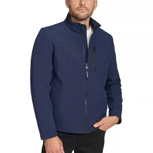 A man is wearing a navy blue zip-up jacket with a standing collar, two side pockets, and a zippered chest pocket, paired with black pants.
