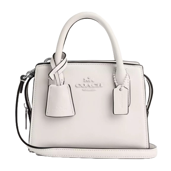 A white leather Coach Outlet Carryall handbag featuring dual top handles, a detachable shoulder strap, and signature Coach branding. It includes two hanging tags with a subtle, minimalist design.