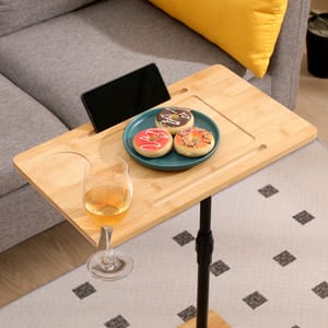 A small wooden side table holds a plate with three decorated cookies, a glass of white wine, and a tablet propped up in a slot.