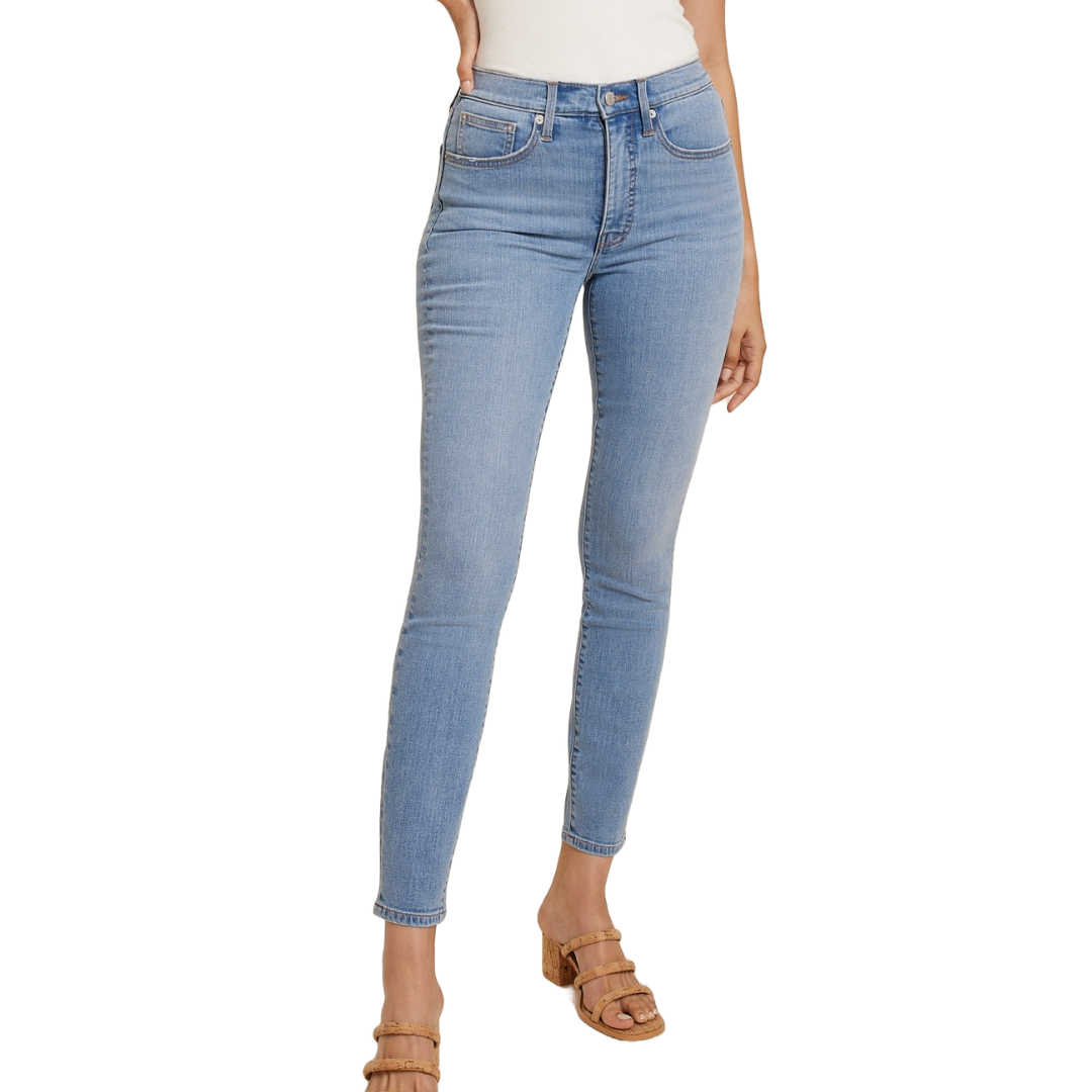 Light blue skinny jeans with a high-rise waist, featuring classic five-pocket styling and a button-zip closure, paired with tan, strappy sandals.
