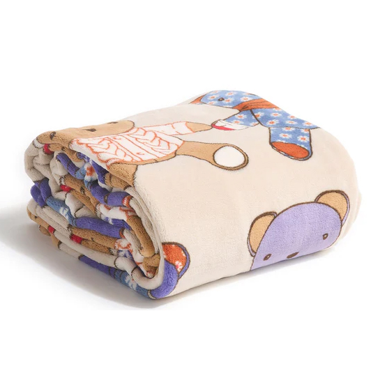 A soft, beige throw blanket featuring a playful teddy bear design with colorful patterns, perfect for adding a touch of whimsy to a child's room or for cozy relaxation.