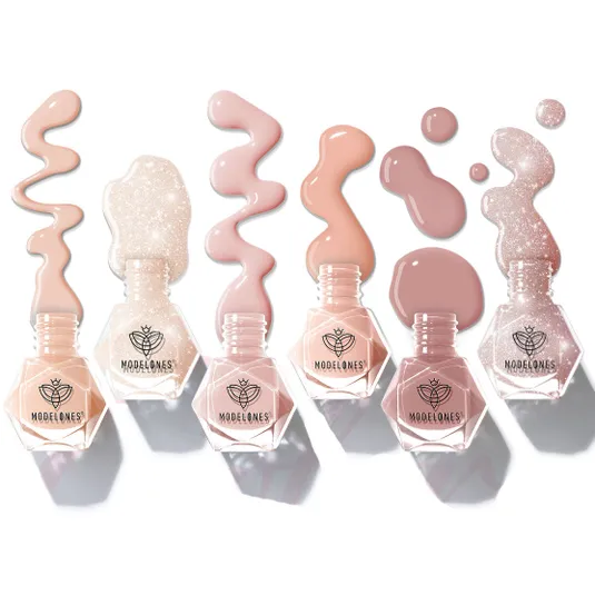 Modelones nail polish bottles are arranged in a row, featuring a variety of nude and glittery shades with decorative spills around them.
