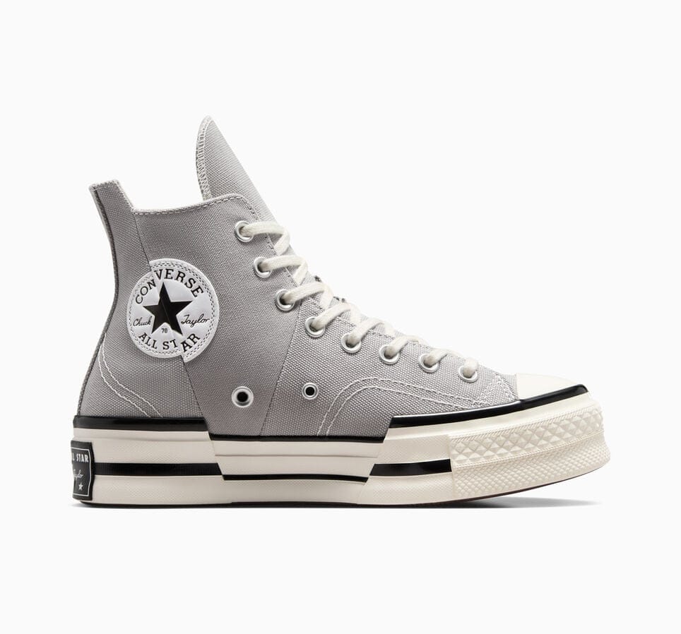 A pair of high-top Converse Chuck 70 sneakers with an elevated platform sole, featuring a classic logo on the inner ankle and a gray canvas upper.