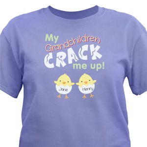 Purple T-shirt featuring the phrase \“My Grandchildren CRACK me up!\“ with cartoon chicks named Jane and Henry.
