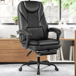 A black leather office chair with a high back, quilted design, adjustable armrests, and a retractable footrest, placed on a gray carpet in front of a wooden cabinet and window.