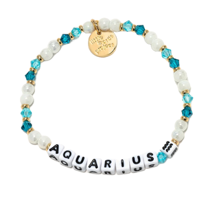 Beaded bracelet with \“AQUARIUS\“ spelled out, featuring blue and white beads, gold accents, and a round charm with \“little words project\“ engraved on it.