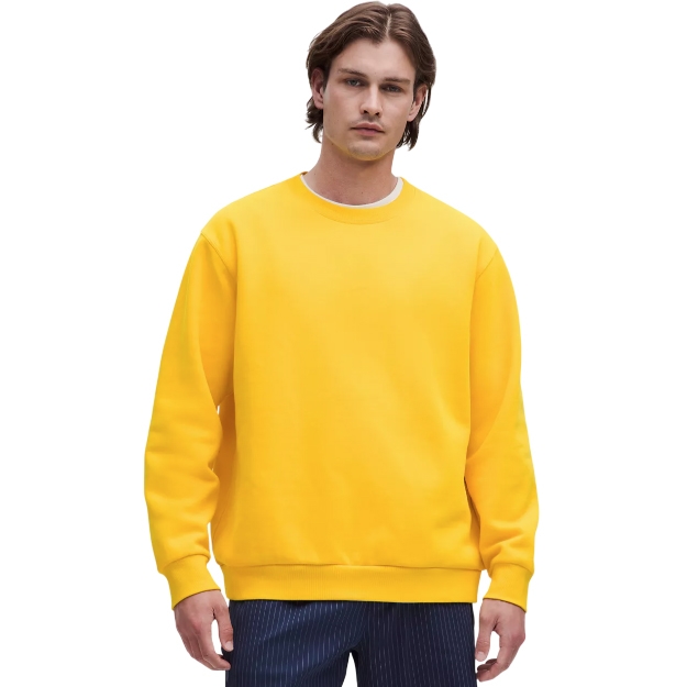 A man wearing a bright yellow crew neck sweatshirt paired with dark pinstriped pants against a plain background.