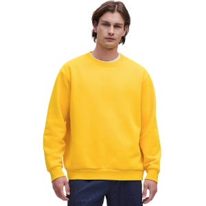 A man wearing a bright yellow crew neck sweatshirt paired with dark pinstriped pants against a plain background.