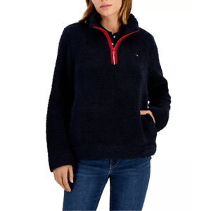 A navy Sherpa pullover jacket with a plush texture, featuring a red half-zip closure and a small logo on the chest, paired with blue jeans.