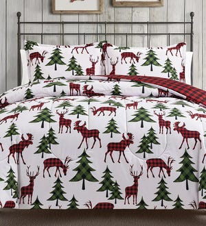 A bedding set featuring red and black buffalo plaid reindeers and green trees on a white background, with a reversible side showing red and black plaid.