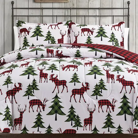 A bedding set featuring red and black buffalo plaid reindeers and green trees on a white background, with a reversible side showing red and black plaid.