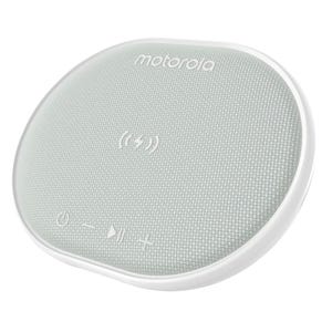 A circular Motorola device combining a wireless charging pad and Bluetooth speaker, with a fabric top featuring touch controls for power, volume, and play/pause, along with a charging icon.