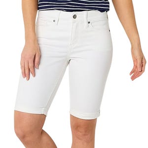 White knee-length denim shorts with a cuffed hem, front button, and zip closure, paired with a navy and white striped top.