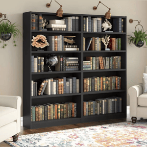 A black bookshelf with six shelves is filled with an assortment of books. Decorative items like a globe, coral sculptures, and a wall-mounted lamp enhance its appearance, and a floral-patterned rug and white armchair are positioned nearby for a cozy reading nook.
