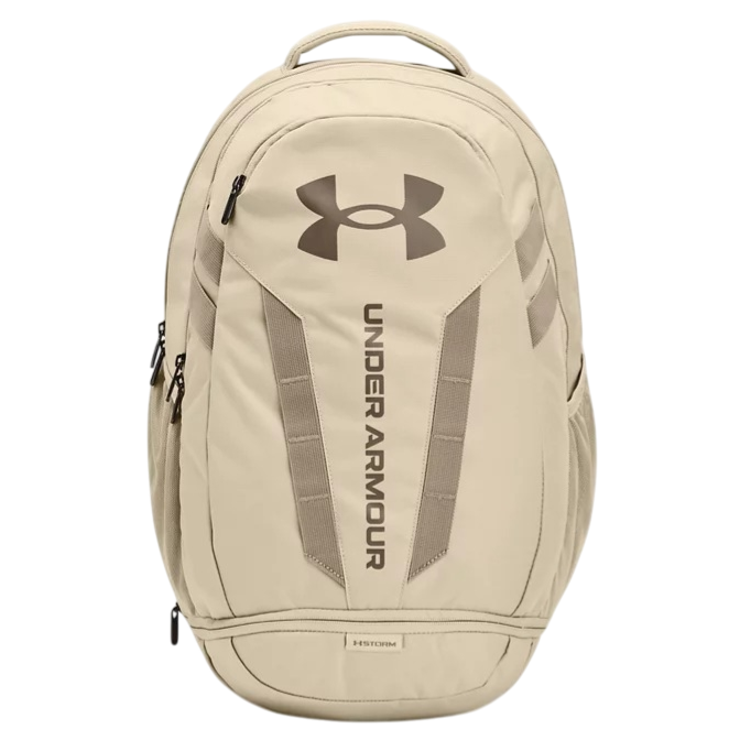 A tan Under Armour backpack with a large logo and vertical branding on the front, featuring multiple compartments and zipper closures.
