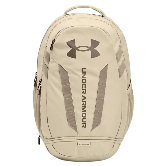 A tan Under Armour backpack with a large logo and vertical branding on the front, featuring multiple compartments and zipper closures.