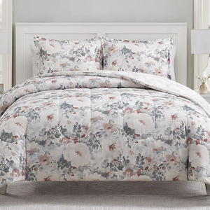 The 3pc Sunham Comforter Set features a floral pattern with soft, muted colors of gray, white, and pink. It includes a comforter and two matching pillow shams, creating a cohesive, elegant bedding look.