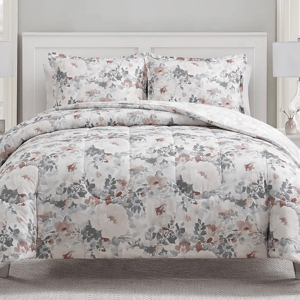 The 3pc Sunham Comforter Set features a floral pattern with soft, muted colors of gray, white, and pink. It includes a comforter and two matching pillow shams, creating a cohesive, elegant bedding look.