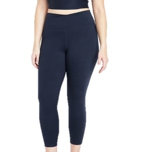 A woman is wearing navy blue high-waisted leggings paired with a matching cropped top.