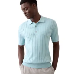 A man is wearing a light blue, short-sleeve, ribbed knit polo shirt paired with light-colored pants.