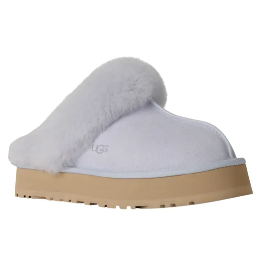A white UGG slipper with a fluffy trim, featuring a thick beige sole and the UGG logo embossed on the side.