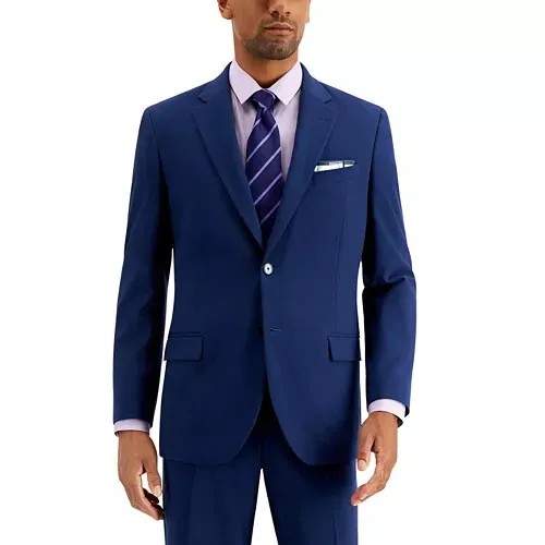 A man wearing a blue two-piece suit with a white dress shirt, a purple striped tie, and a pocket square.