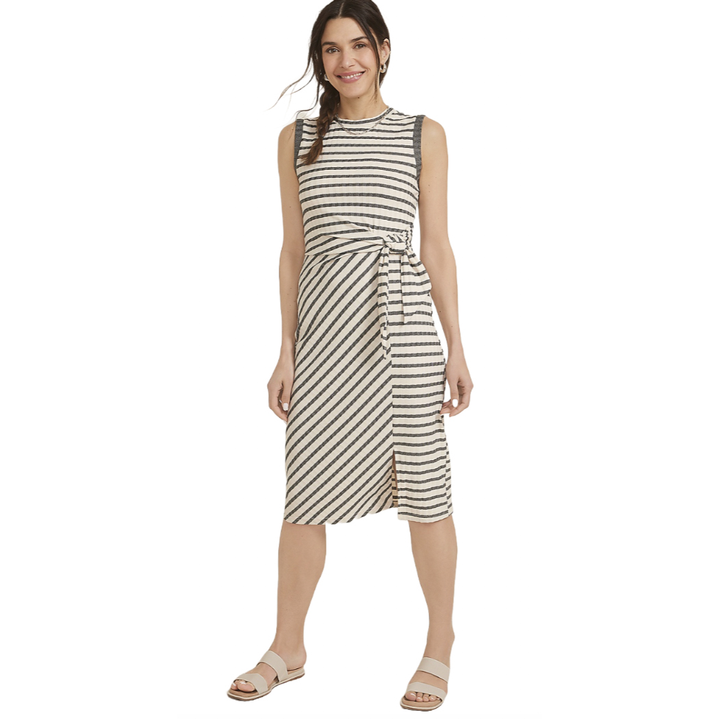 Sleeveless striped dress with a waist tie, featuring a knee-length hem and side slit, paired with flat sandals.
