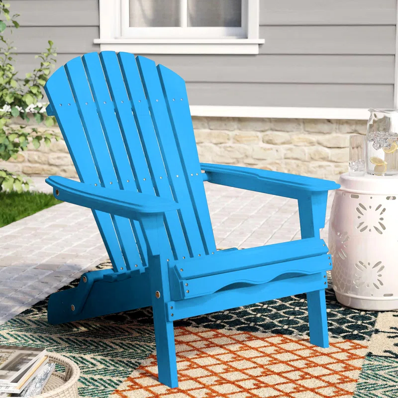 A bright blue Adirondack chair on an outdoor rug, with a small white side table.