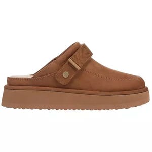 A tan slip-on mule with a thick sole and adjustable strap, featuring a subtle stitched design and a small metal accent.