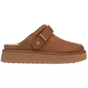 A tan slip-on mule with a thick sole and adjustable strap, featuring a subtle stitched design and a small metal accent.