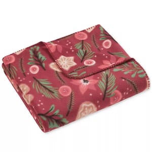 A red fleece blanket with a festive design featuring pine branches, pink flowers, and stars.