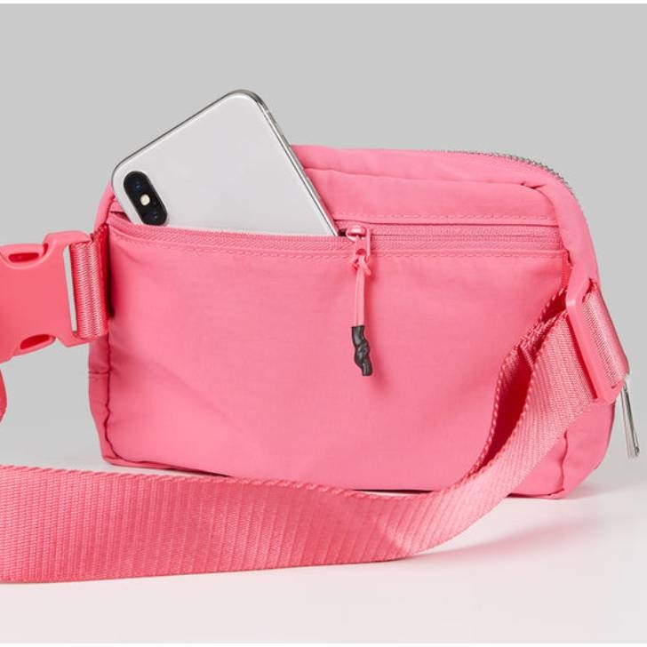 A pink waist bag with a smartphone peeking out of its open compartment.