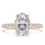 A rose gold engagement ring featuring a large oval diamond set in a four-prong setting, with a band adorned with smaller diamonds.