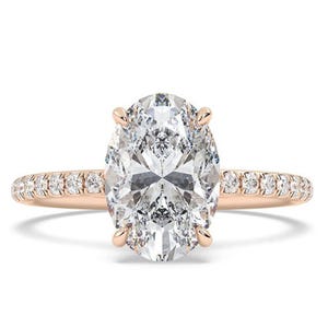 A rose gold engagement ring featuring a large oval diamond set in a four-prong setting, with a band adorned with smaller diamonds.