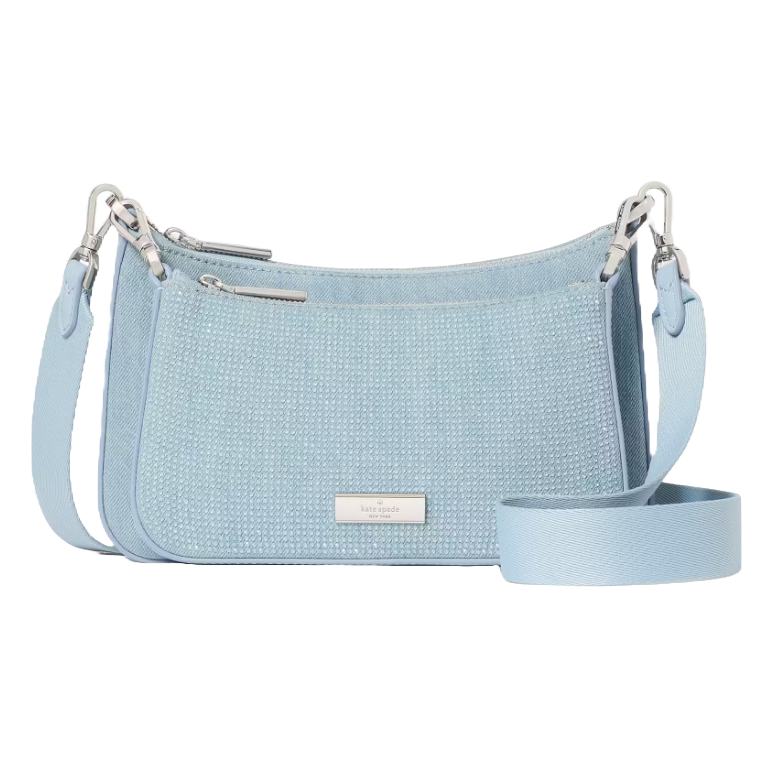 The Kate Spade Duet Crossbody is a light blue, textured bag with silver hardware. It features a detachable strap and a front logo plate.