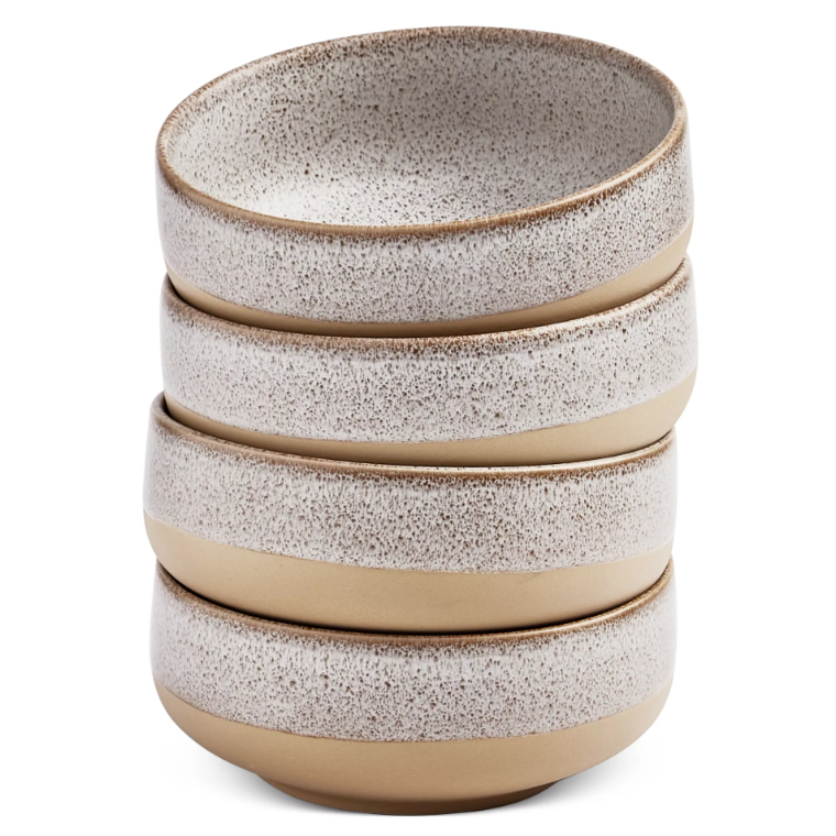 A stack of four stoneware bowls with a speckled white interior and a matte light brown exterior.