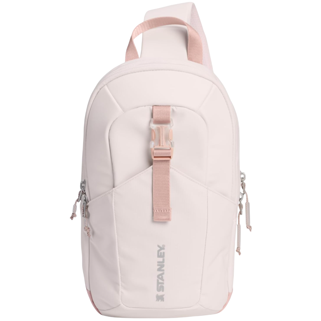 A pale pink Stanley backpack featuring a main compartment with a zipper closure, an additional front buckle strap, and two side zipper pockets for extra storage.