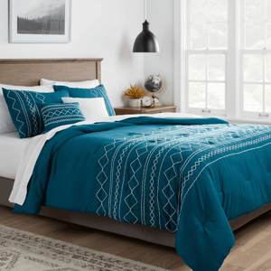 A teal 5-piece queen comforter set featuring white geometric embroidery, including a comforter, two pillow shams, and two decorative pillows. The set is displayed on a bed with a modern wooden headboard in a bright, well-lit room.