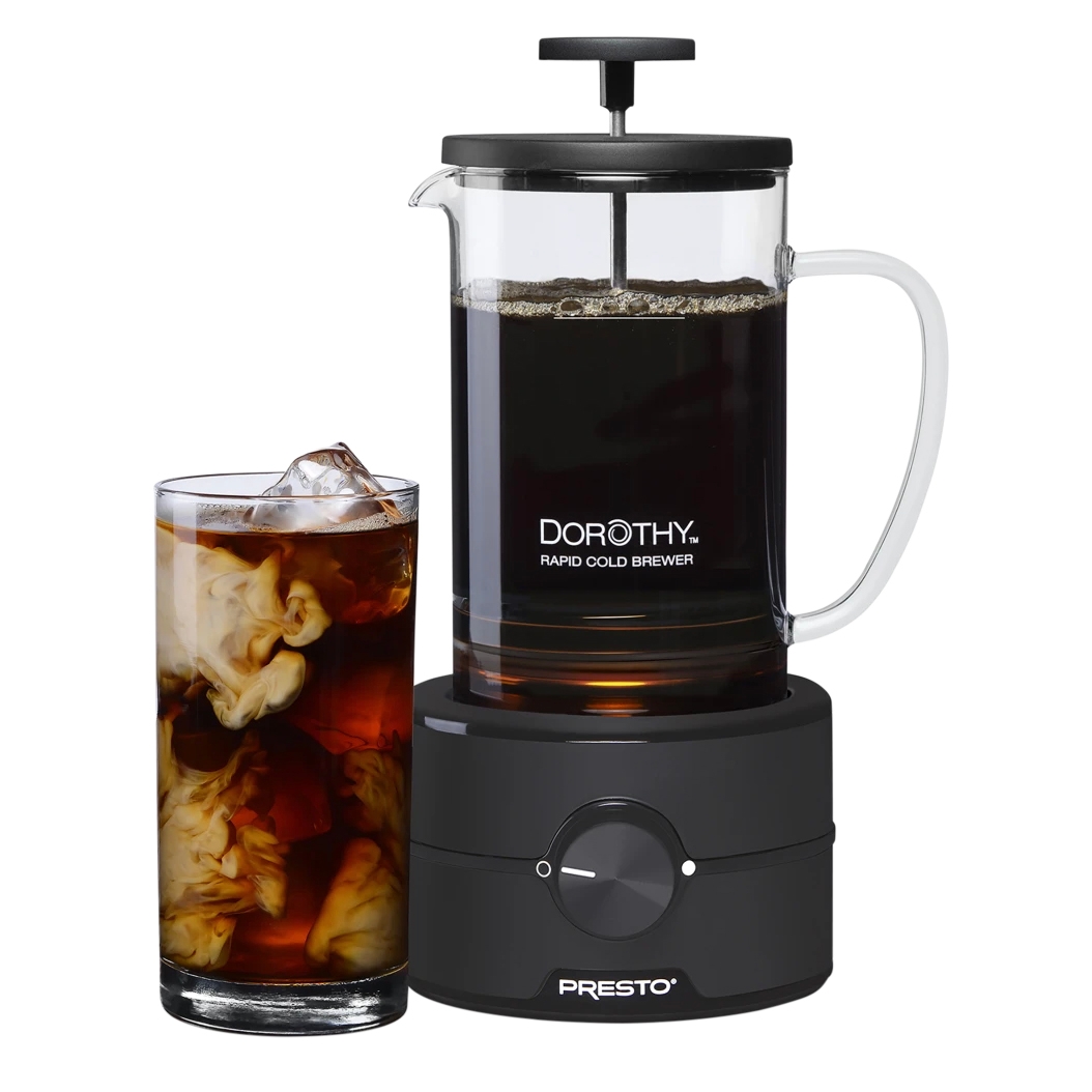 A glass and black 22oz cold brew coffee maker with \“DOROTHY Rapid Cold Brewer\“ branding, featuring a plunger and handle. A glass with swirling iced coffee sits next to it.