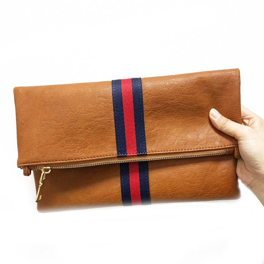A brown faux-leather clutch with a fold-over design and a central blue and red stripe. It features a gold zipper closure.