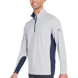 A man is wearing a light gray long-sleeve quarter-zip pullover with navy accents and a small puma logo on the sleeve.