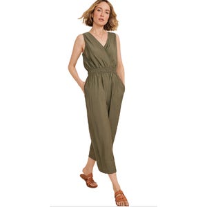 Olive green sleeveless jumpsuit with a V-neck wrap front, elastic waistband, and cropped wide legs. Paired with brown flat sandals.