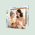 A framed canvas print features two smiling women, one holding a bouquet and the other holding a wrapped gift, conveying a moment of joy and connection.