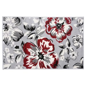 A decorative rug featuring a floral pattern in red, black, and white against a gray background.