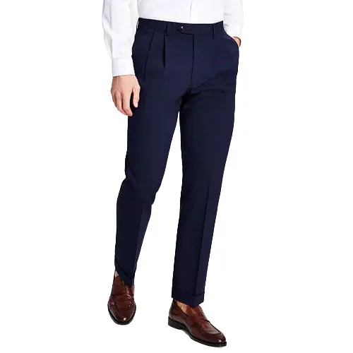 A person wearing dark blue pleated trousers with a white shirt and brown dress shoes.