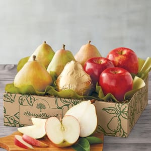 A selection of fresh pears and apples, with one pear wrapped in gold foil, arranged in a branded cardboard box.