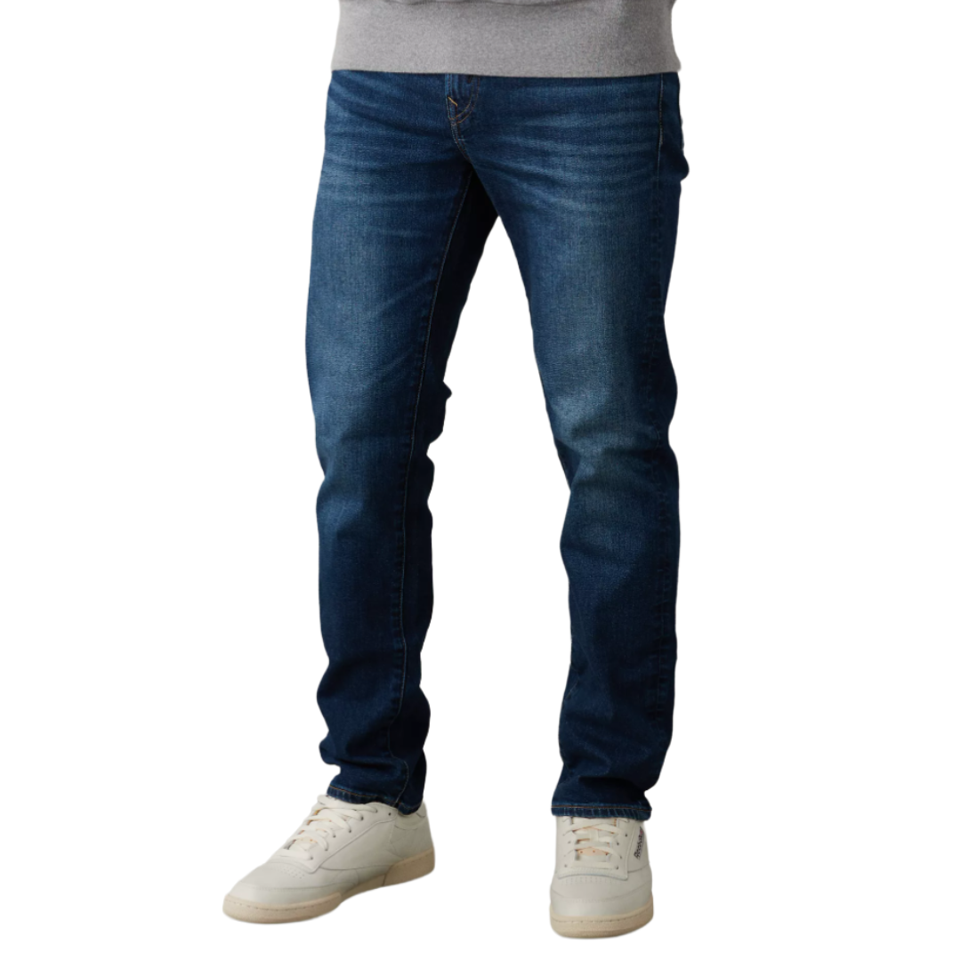 Dark blue slim-fit jeans paired with white sneakers, worn with a gray sweatshirt.