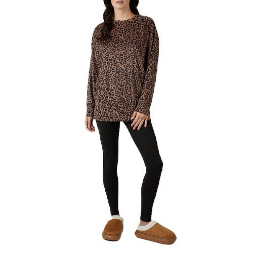 A person is wearing a leopard print long-sleeve top, black leggings, and brown fuzzy slippers.