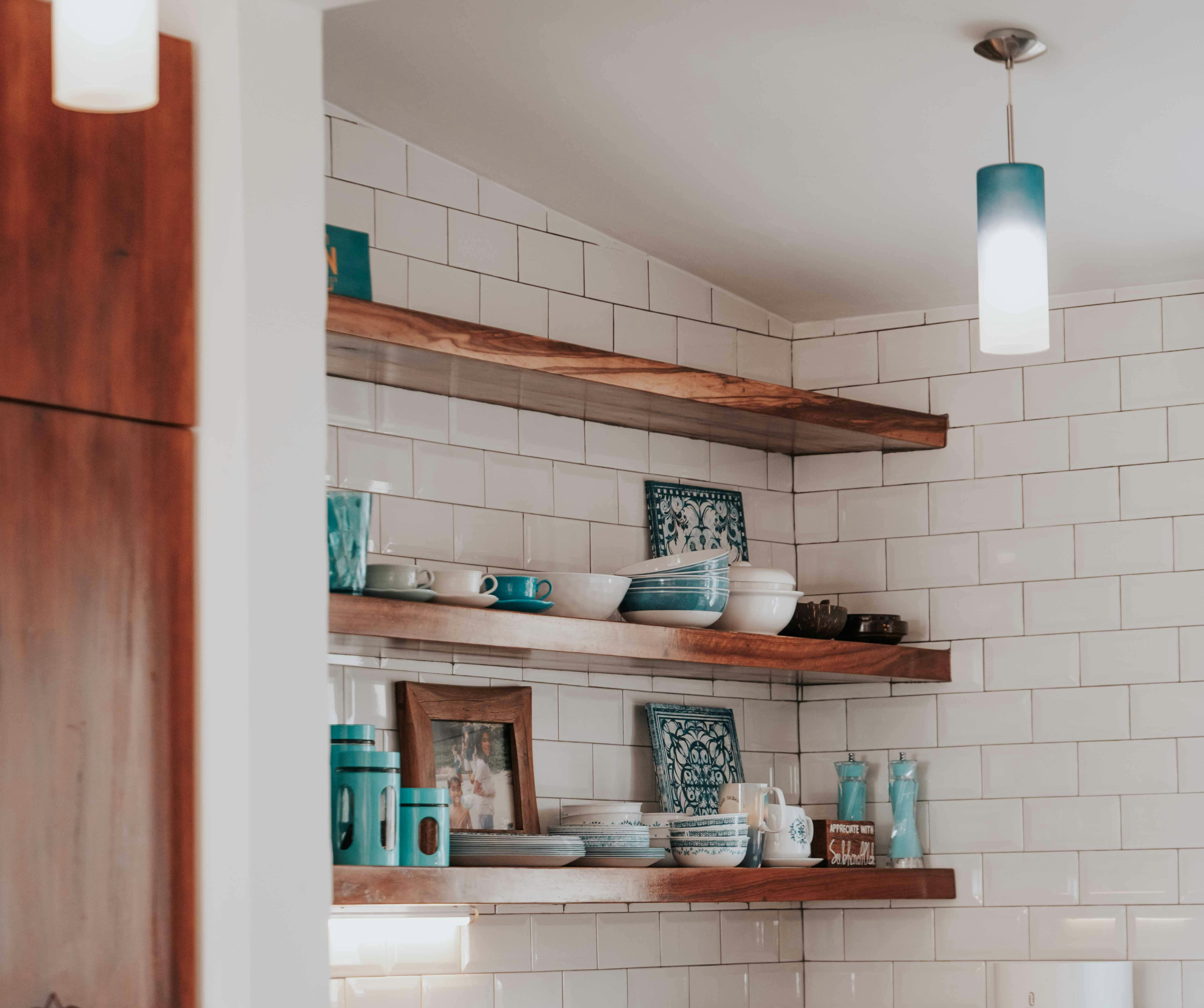 Kitchen shelves with assorted dishes, cups, and decorative items in white and turquoise colors.