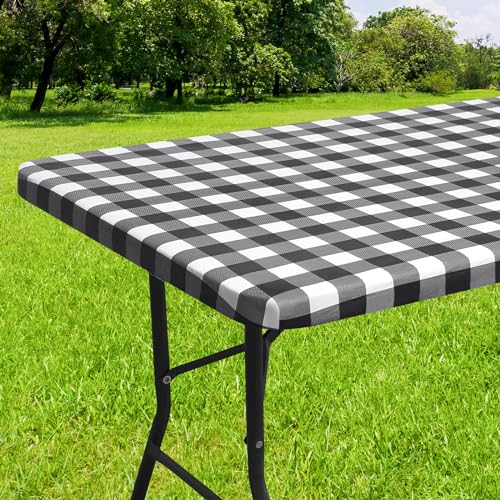 A black and white checkered vinyl tablecloth is covering an outdoor table, set against a grassy background.